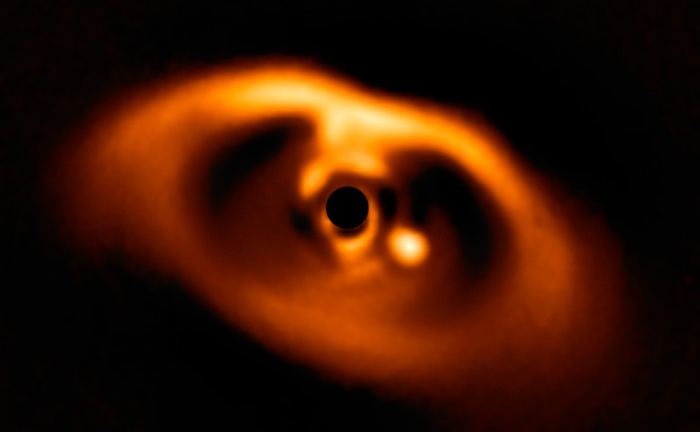 ภาพดาวเคราะห์ชื่อ พีดีเอส 70 บี (จุดขาว) ที่กำลังก่อตัวขึ้นภายในจานกำเนิดดาวเคราะห์ของดาวพีดีเอส 70 (อยู่ในวงกลมดำกลางภาพ) ถ่ายโดยอุปกรณ์ชื่อสเฟียร์ของกล้องวีแอลที 