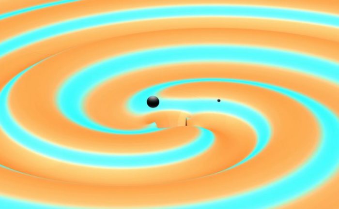 ภาพจำลองหลุมดำสองดวงที่ตีวงเข้าหากันในช่วงสุดท้ายก่อนจะกลืนกันเป็นดวงเดียว <wbr>พร้อมกับแผ่คลื่นความโน้มถ่วงออกไปรอบทิศ <wbr><br />
<br />
